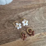 Deux paires de pampilles Anna : une blanche et une marron, posée sur un plateau en bois