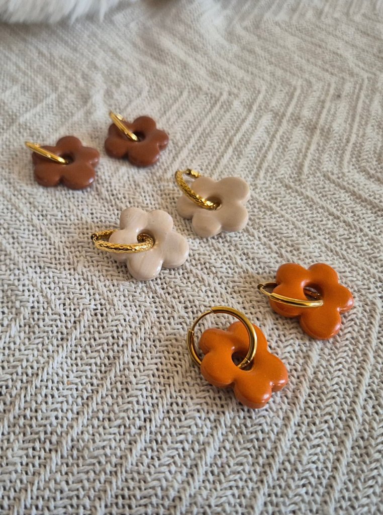 Trois paires de pampilles Alma : marron, beige et orange sur des créoles